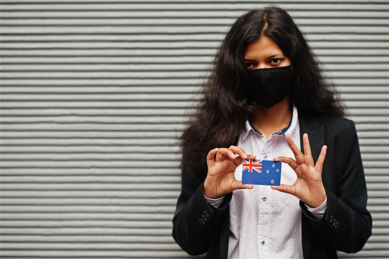 b2ap3_large_asian-woman-formal-wear-black-protect-face-mask-hold-new-zealand-flag-hand-against-gray-background-coronavirus-country-concept 820 Partner Visa Conditions and Obligations - Blog